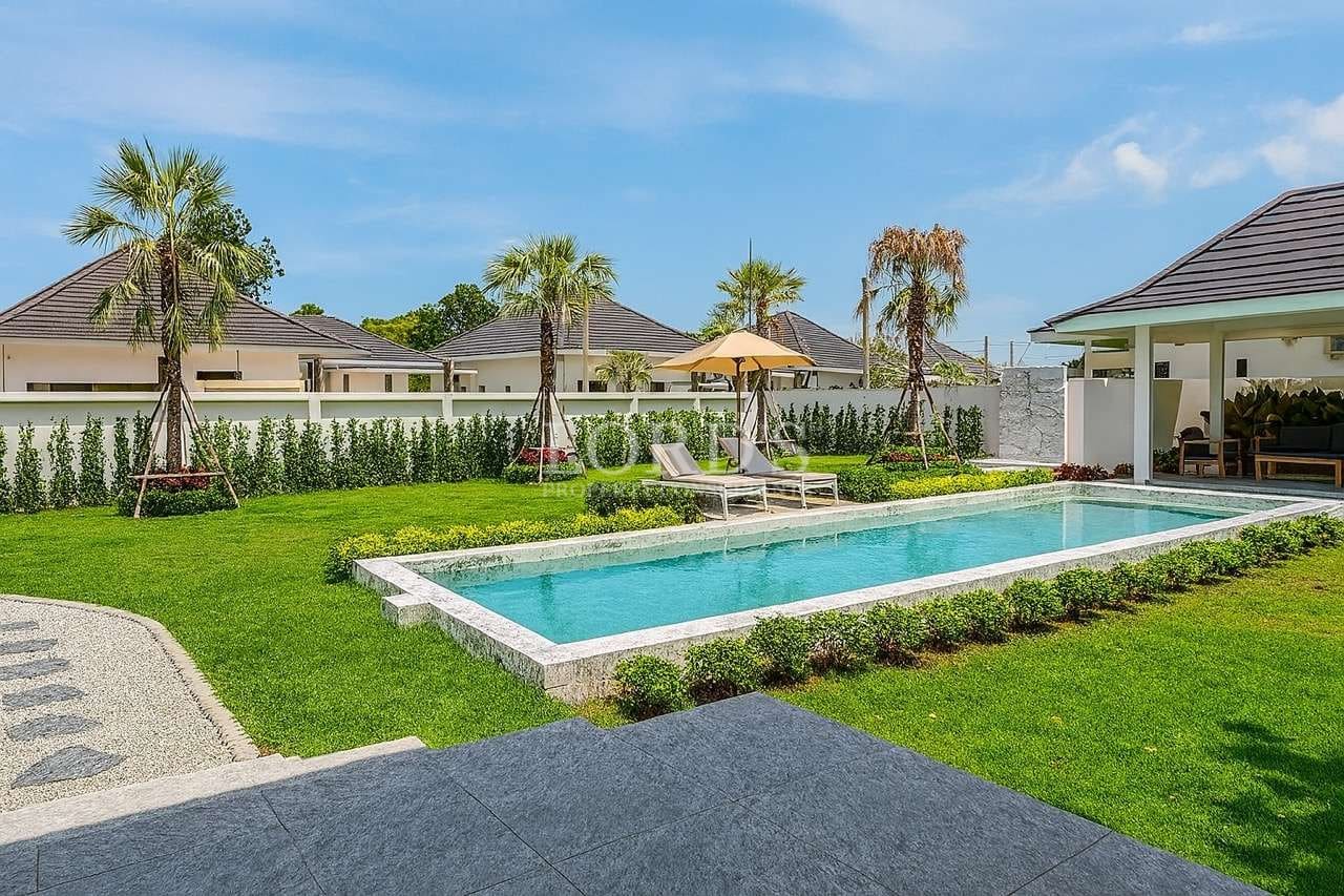 Modern luxury villa with private swimming pool, sun loungers, and landscaped garden