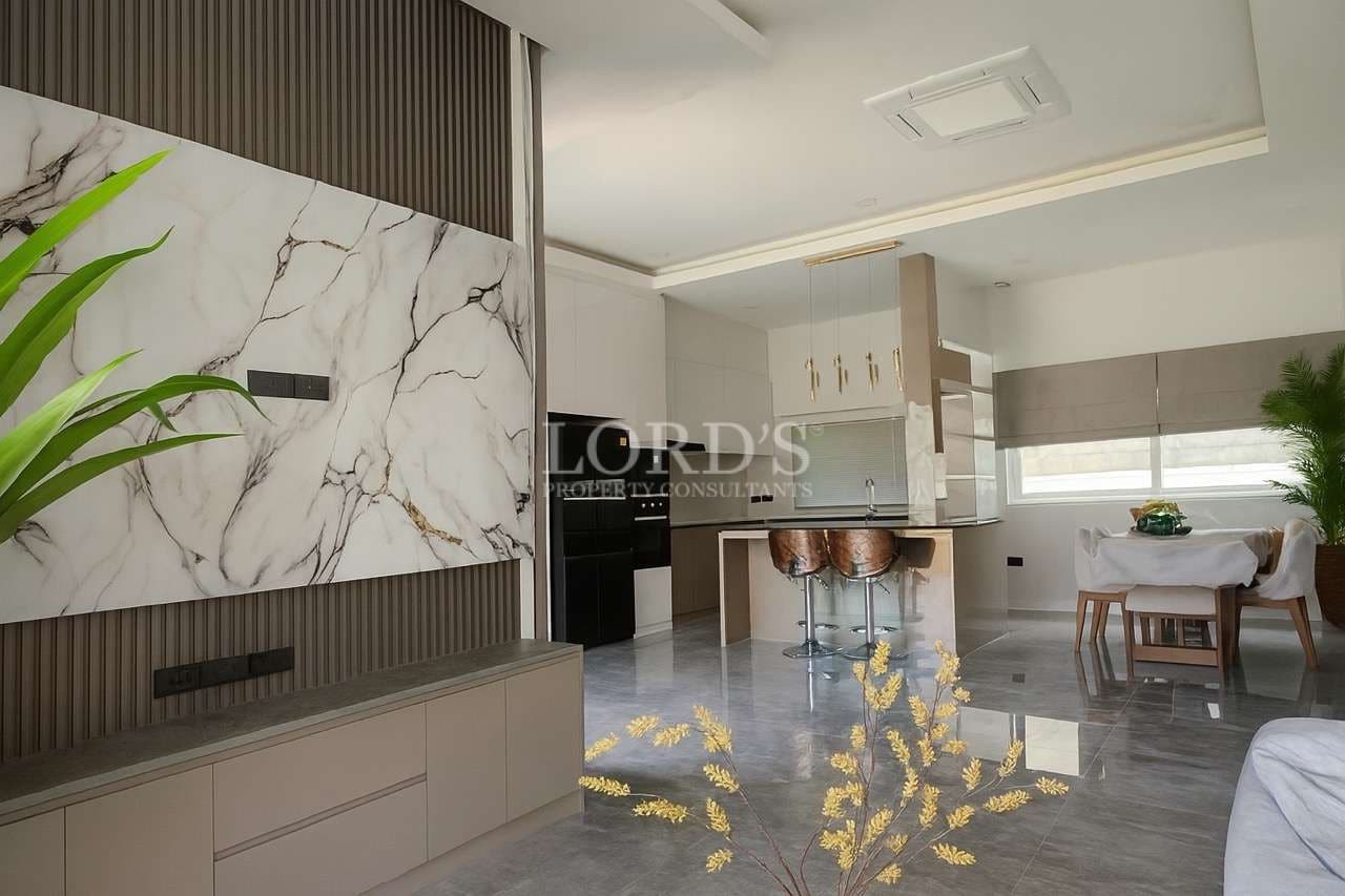 Modern open-plan living area with marble accent wall, kitchen island, and dining space