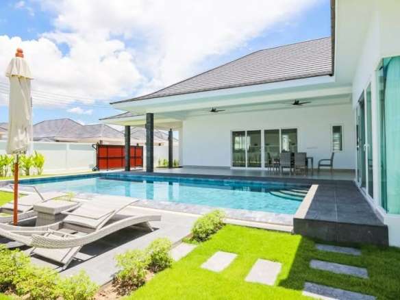 Luxury villa with private swimming pool, sun loungers, and landscaped garden