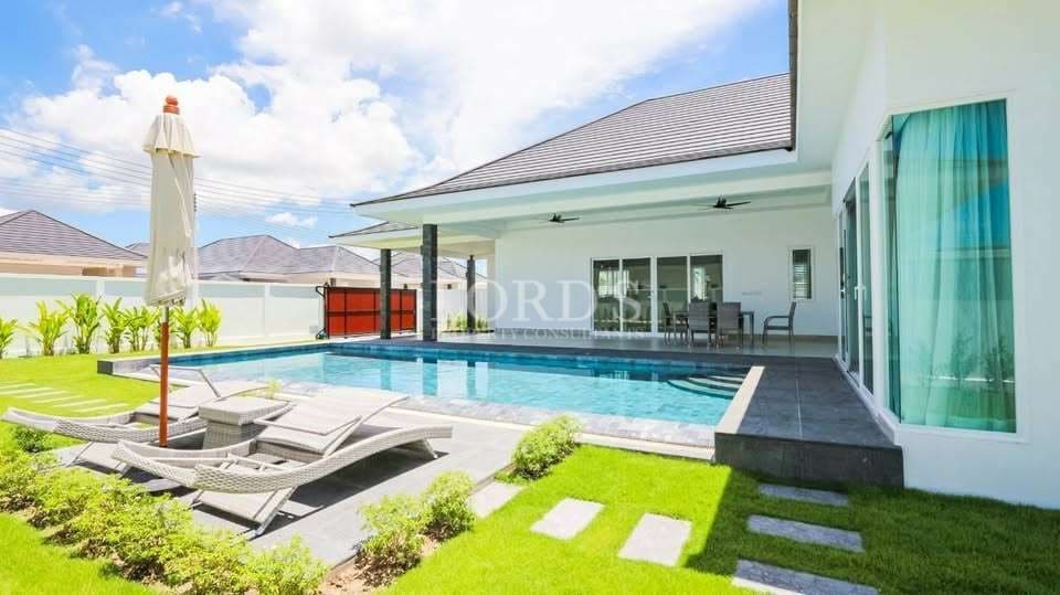 Luxury villa with private swimming pool, sun loungers, and landscaped garden