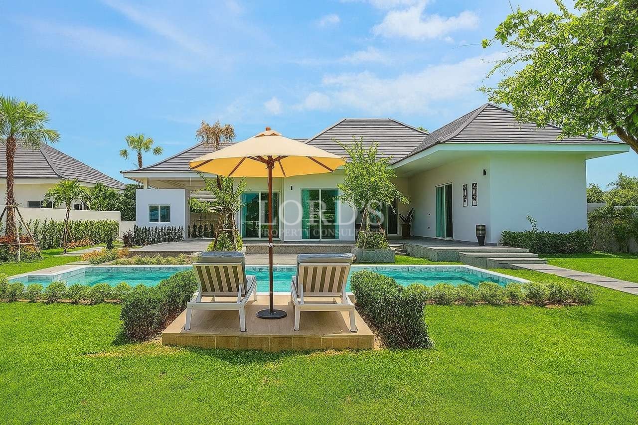 Modern luxury villa with private swimming pool, sun loungers, and landscaped garden