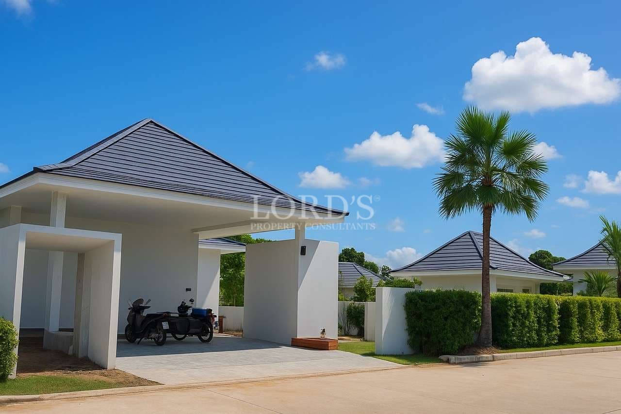 Modern luxury villa exterior with covered carport, palm tree, and landscaped surroundings