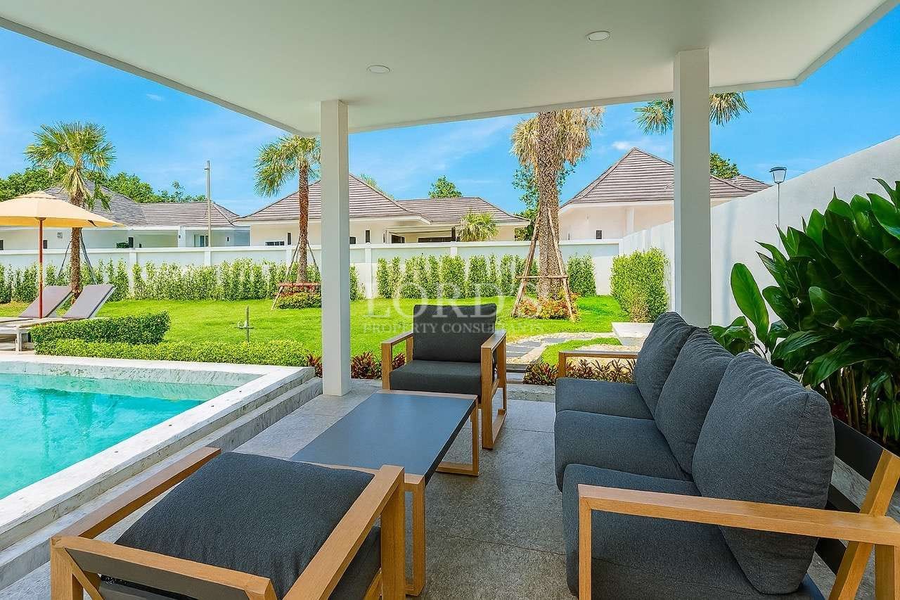 Covered outdoor seating area beside a private swimming pool in a modern luxury villa