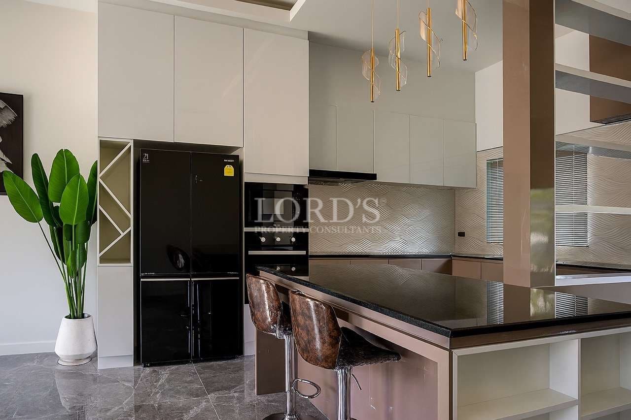 Modern luxury kitchen interior with island counter, bar stools, built-in appliances, pendant lights, and marble flooring