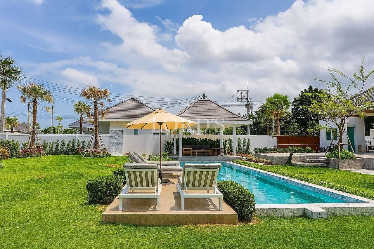 Luxury villa outdoor area with private swimming pool, sun loungers, umbrella seating, and landscaped green garden