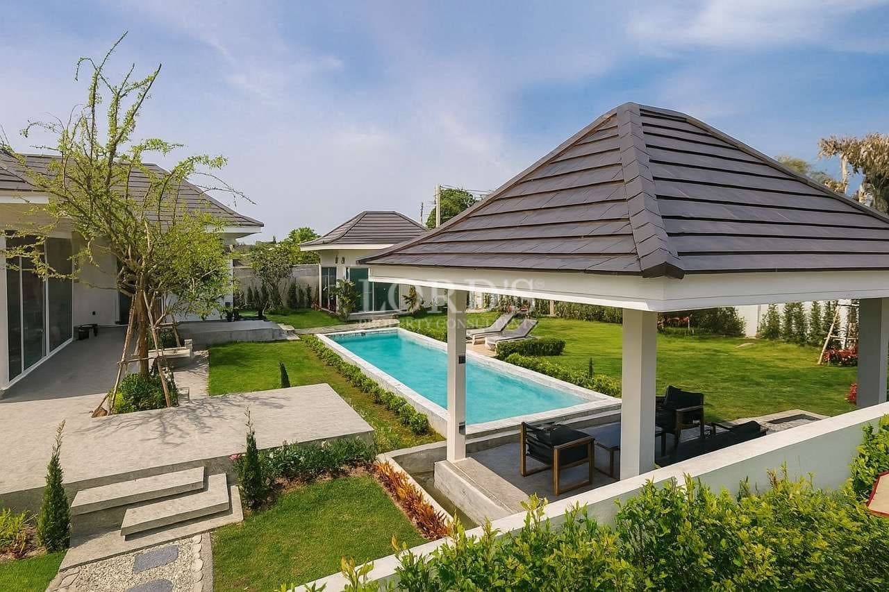 Luxury villa with private swimming pool, garden lawn, and outdoor pavilion seating area.