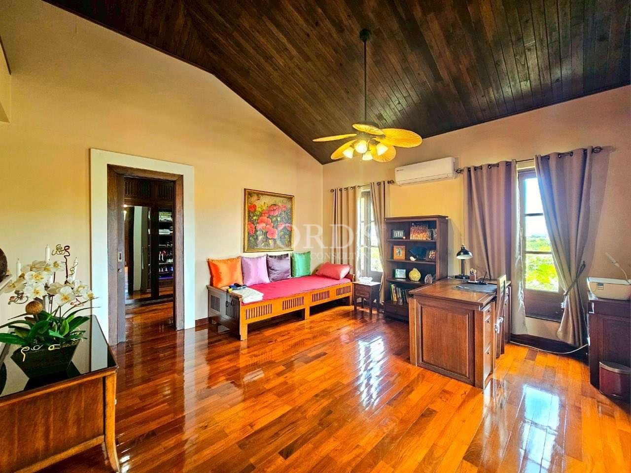 Spacious villa interior with polished wooden floors, high wooden ceiling, and cozy seating area