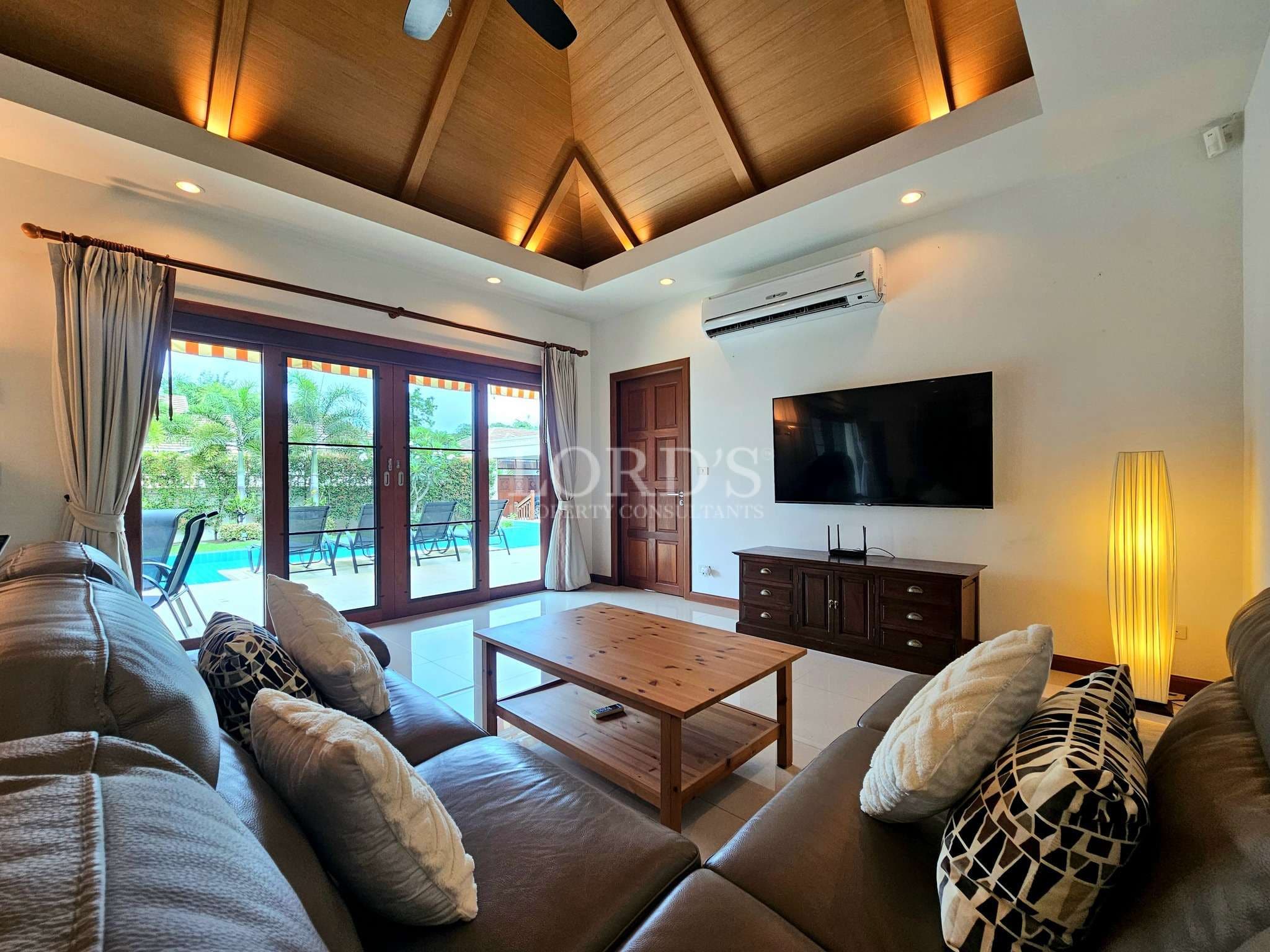 Modern living room with vaulted wooden ceiling and poolside glass doors