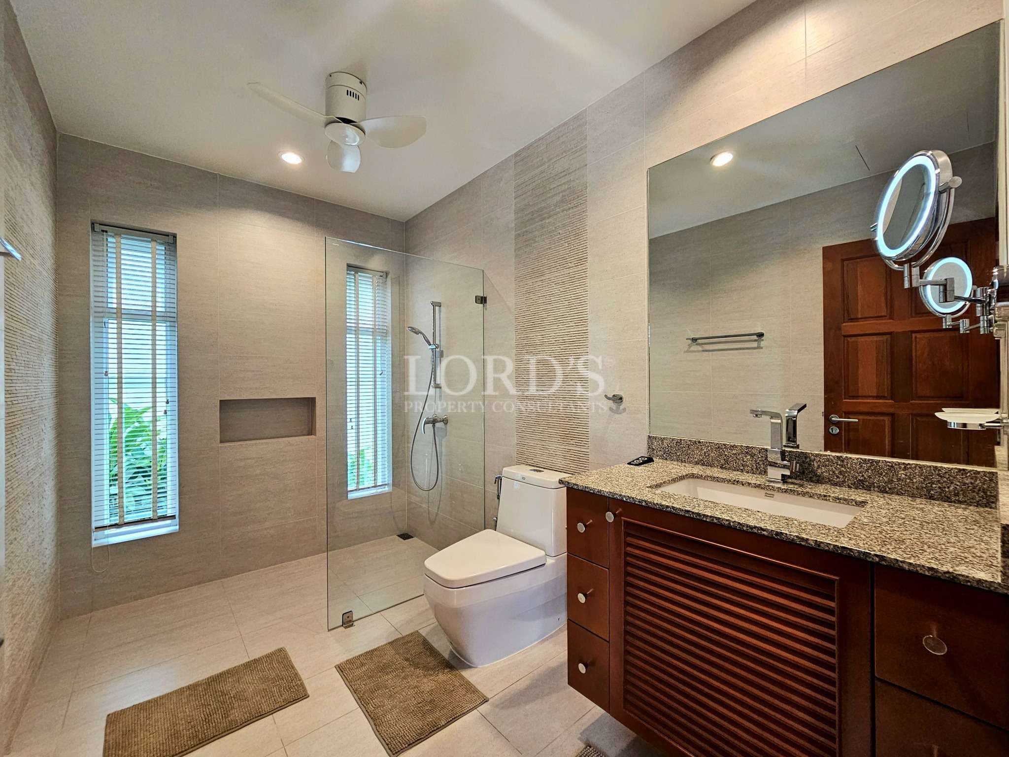 Modern bathroom with glass shower, granite vanity, and natural light