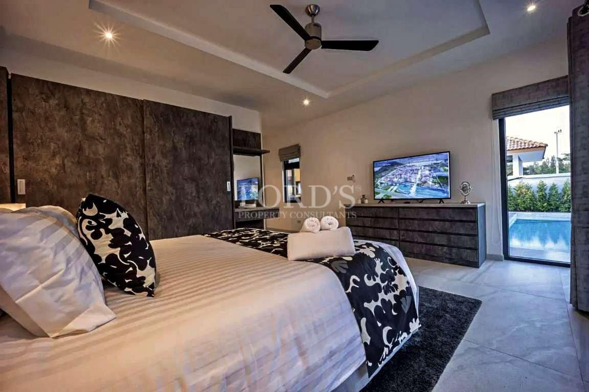 Modern luxury bedroom with king-size bed, textured accent wall, and pool view through sliding glass door