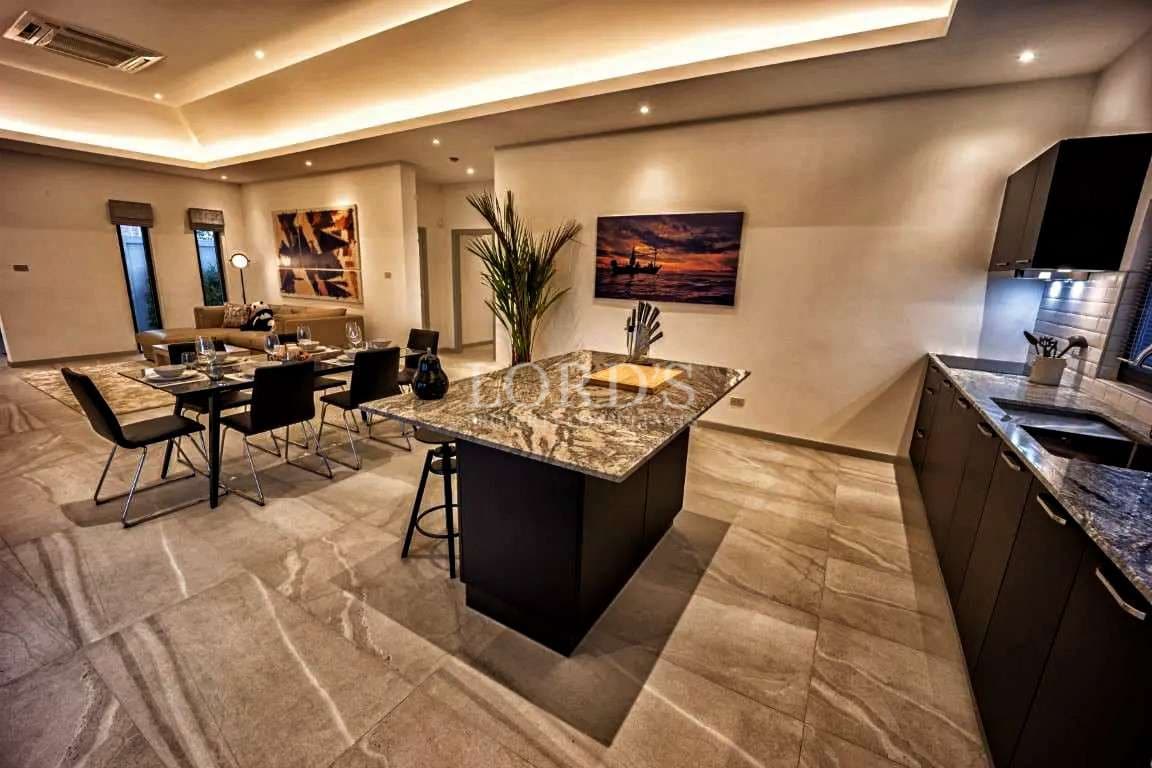 Modern open-plan kitchen and dining area with granite island and ambient lighting