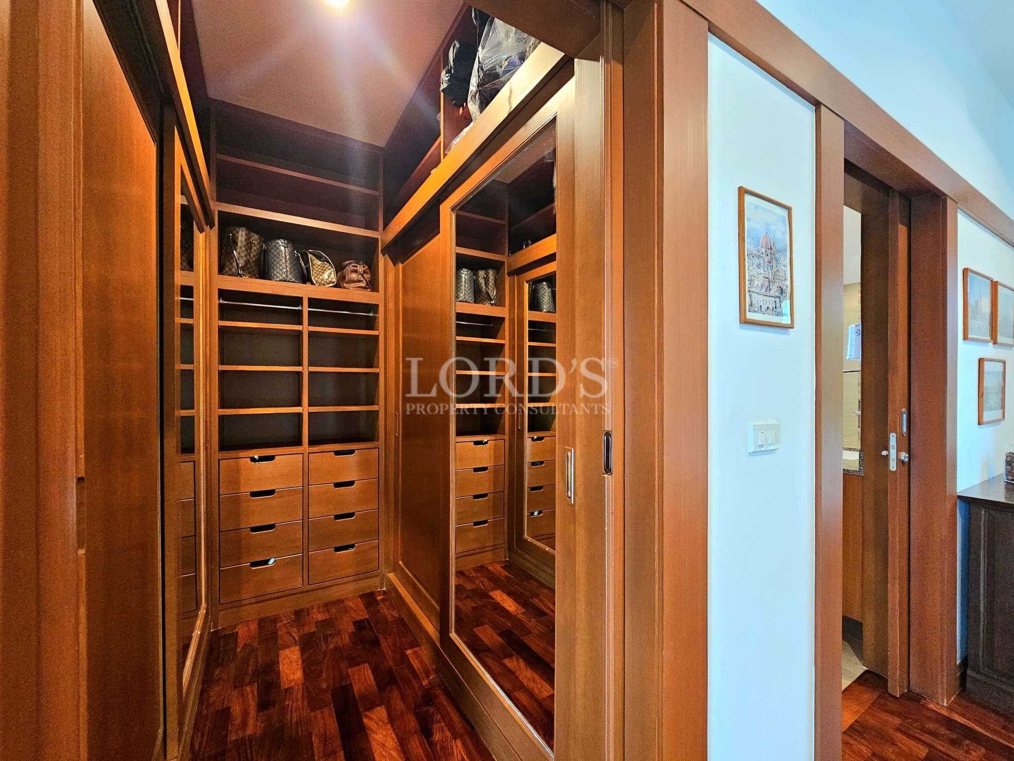 Walk-in wardrobe with wooden shelves, drawers, and mirrored sliding doors