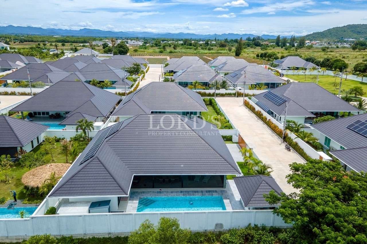 Aerial view of luxury villa community with private swimming pools, landscaped gardens, and mountain views