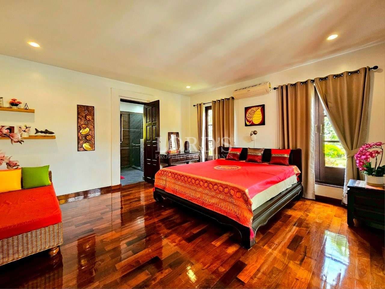 Bright luxury bedroom with red bedding, polished wooden floor, large windows, and modern décor