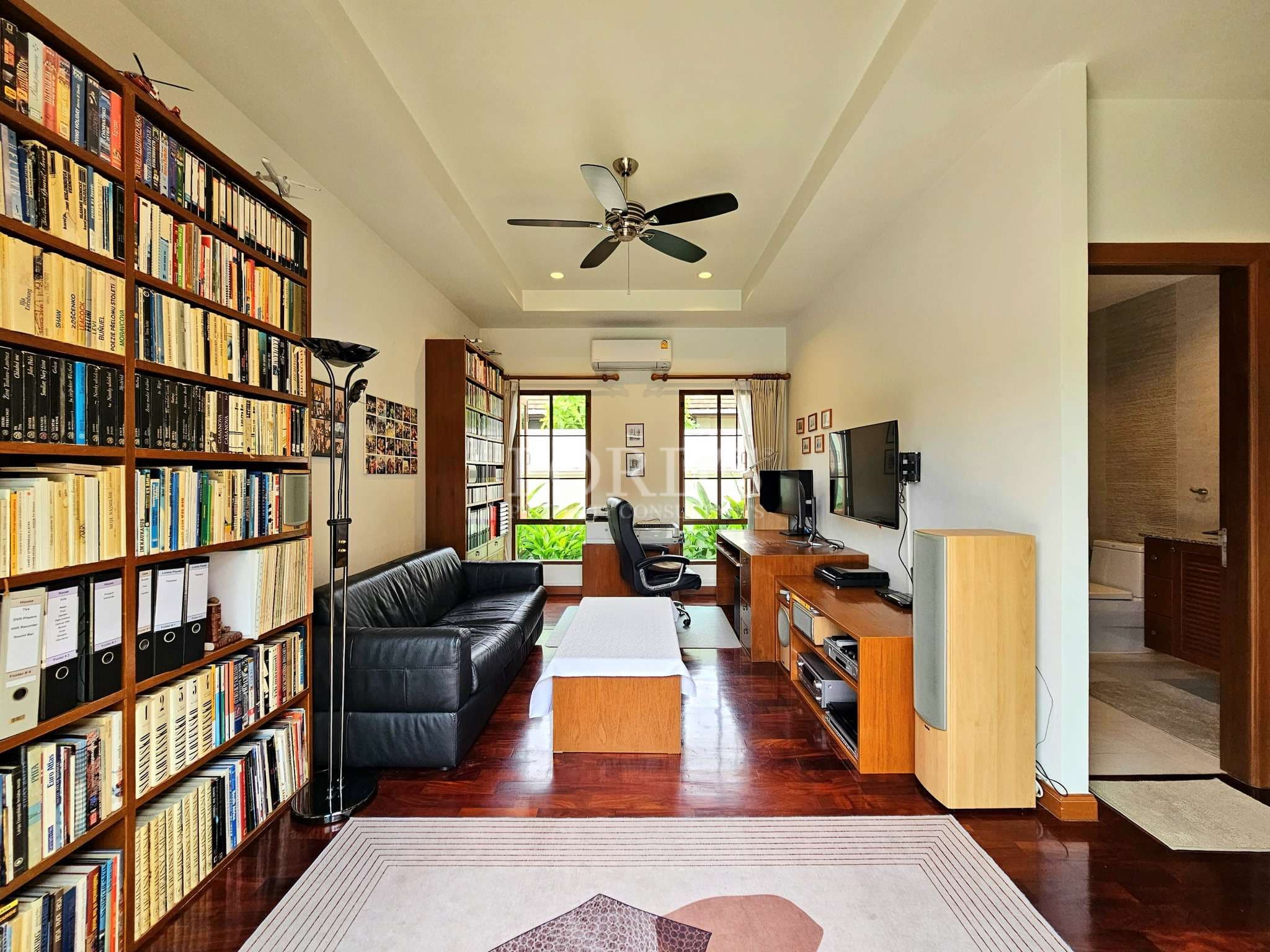 Modern home office and living space with built-in bookshelves, desk area, and TV unit