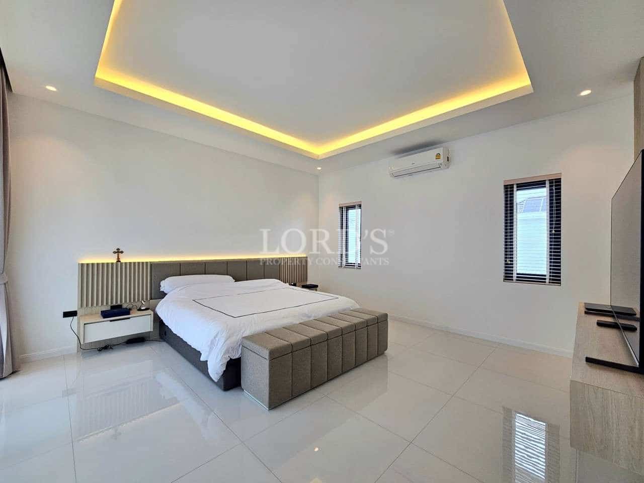 Minimalist bedroom with modern bed, recessed ceiling lighting, and clean white interior