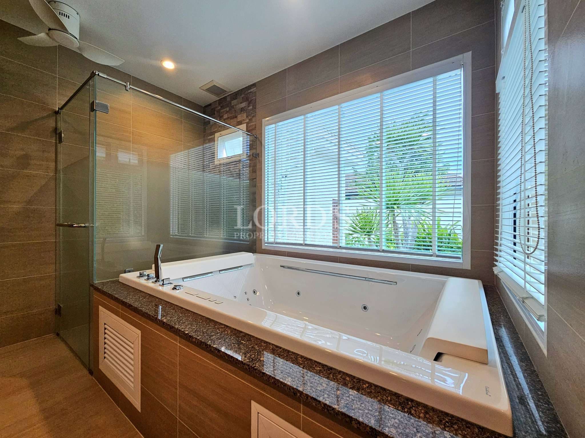 Modern bathroom with jacuzzi bathtub, glass shower enclosure, and large window