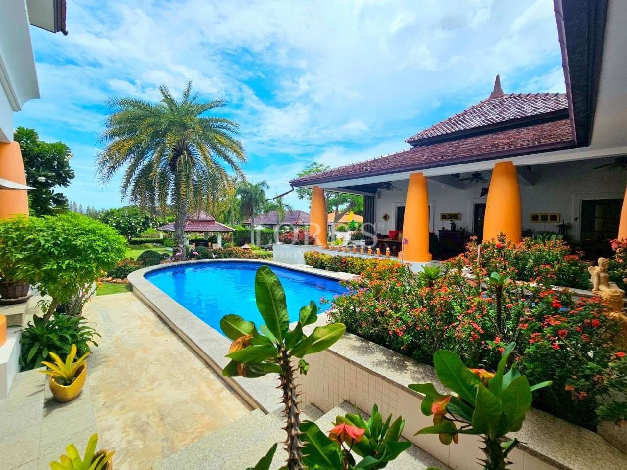Luxury villa with private swimming pool, tropical garden, palm trees, and elegant outdoor seating.