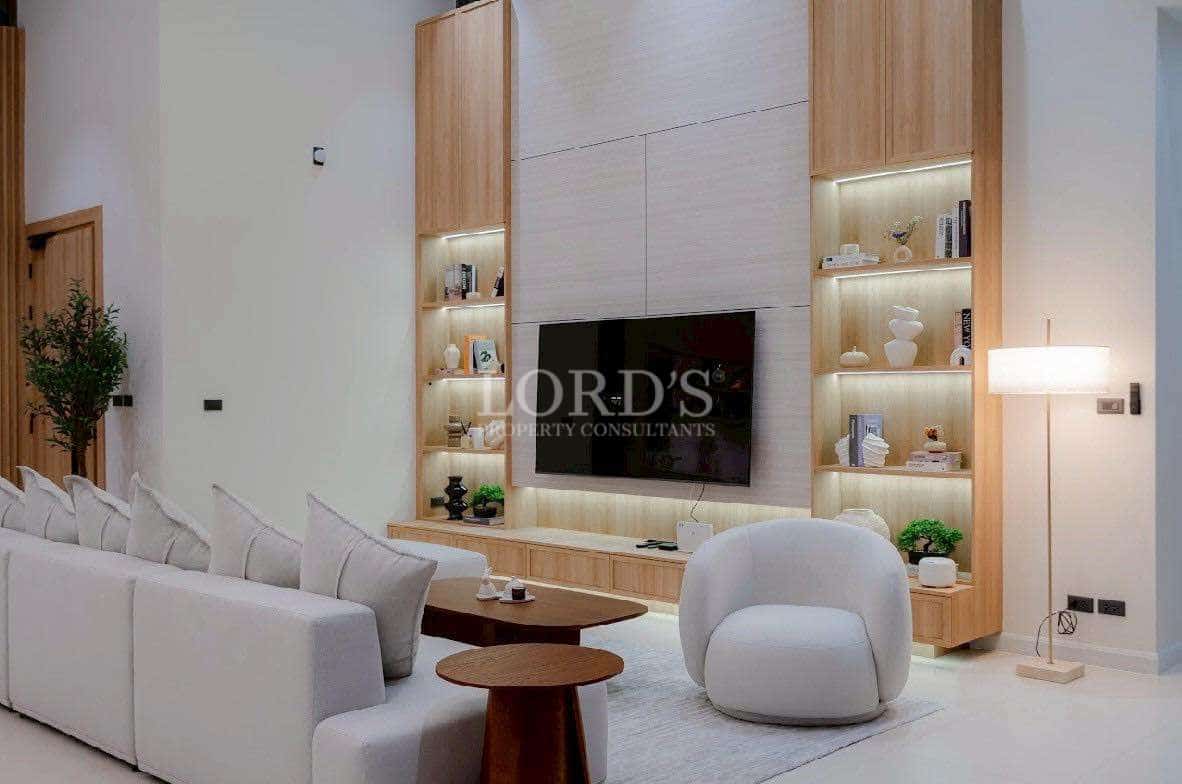 Modern luxury living room with custom TV wall, wooden shelving, and soft ambient lighting.