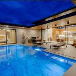 Luxuriöse moderne Villa bei Nacht mit beleuchtetem Privatpool und Sitzbereich im Freien.