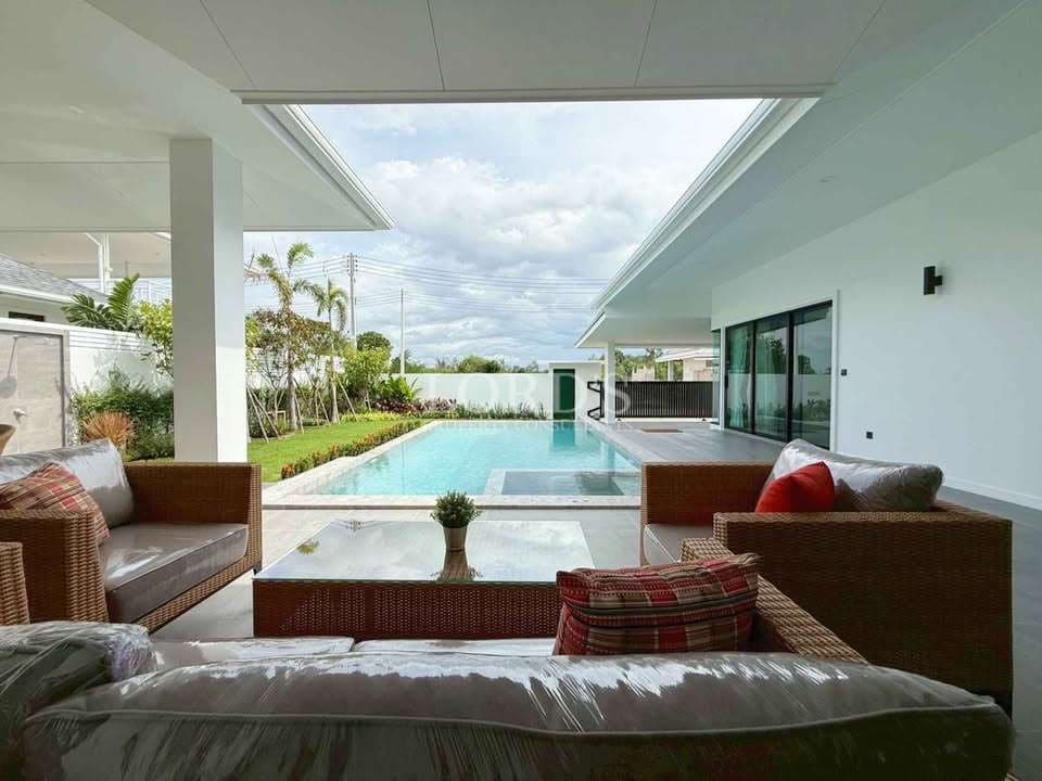 Luxury villa covered outdoor lounge with rattan seating, private swimming pool, and garden view.