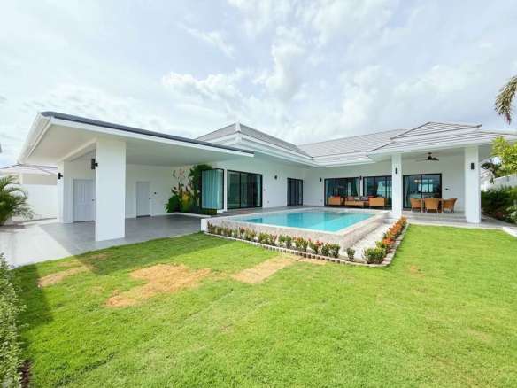 Modern single-story luxury villa with private swimming pool, landscaped lawn, and covered outdoor seating.
