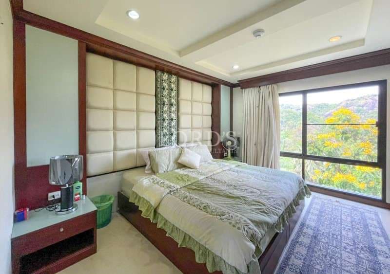 Modern bedroom with padded headboard, large window, and nature view