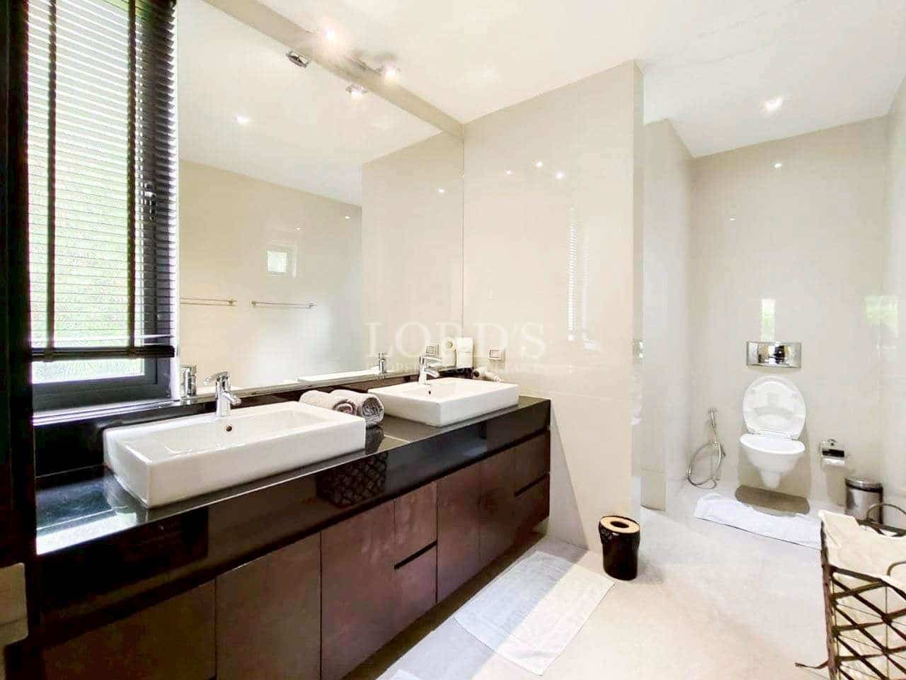 Modern bathroom with double vanity sinks, dark wood cabinets, large mirror, and minimalist white finishes