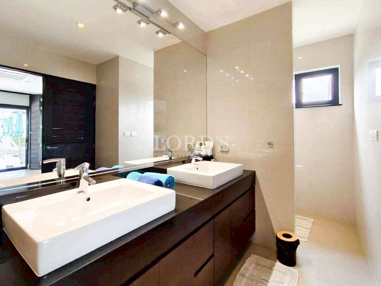 Modern bathroom vanity with double sink, large mirror, and contemporary lighting design
