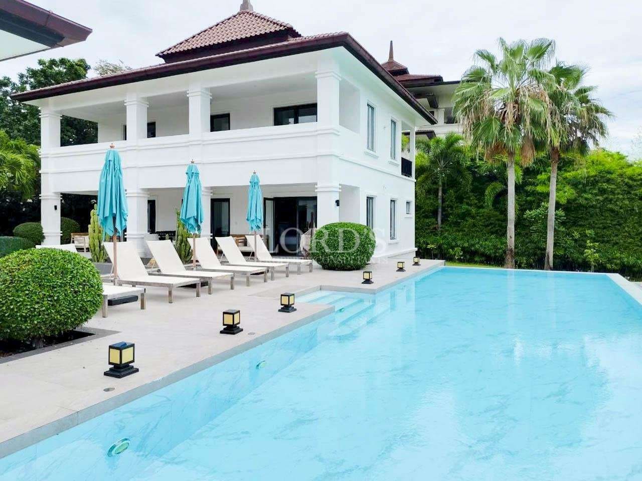 Luxury two-story villa with private swimming pool, sun loungers, and tropical landscaping