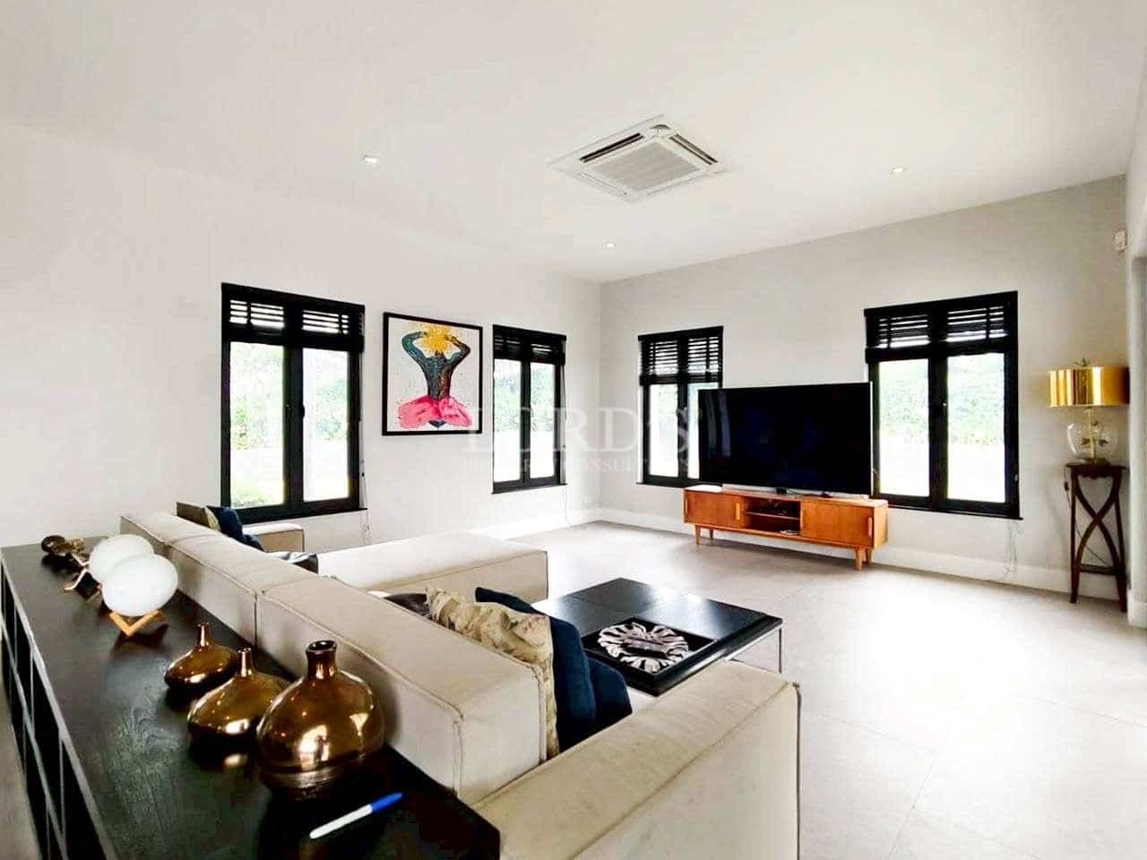 Bright modern living room with sectional sofa, large TV unit, and minimalist interior design