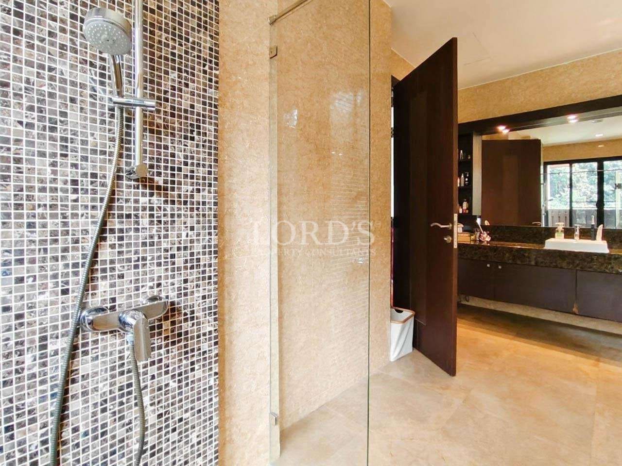 Modern bathroom with walk-in glass shower, mosaic tile wall, and luxury vanity area.