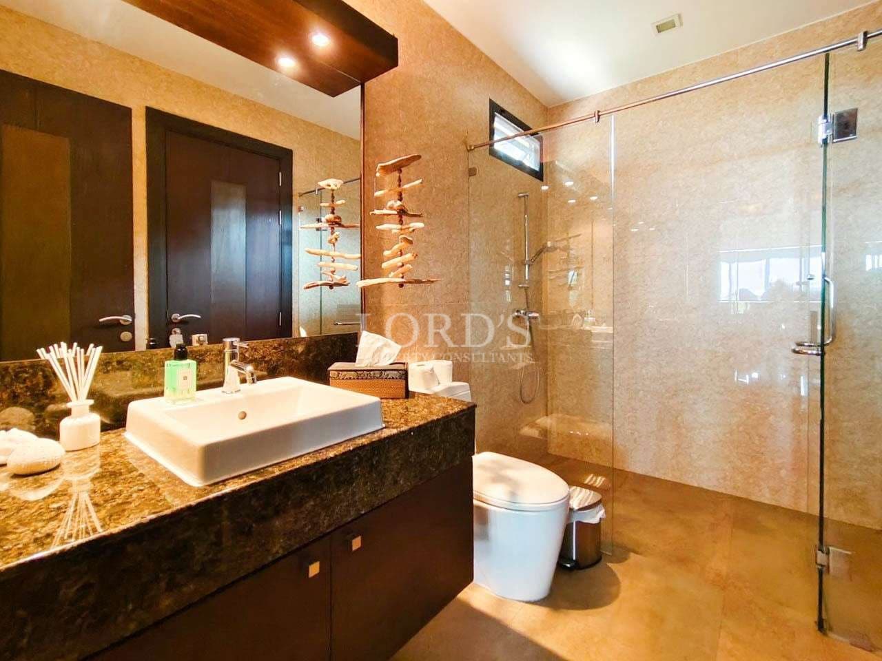 Luxury bathroom with stone tiles, glass shower enclosure, modern vanity sink, and premium fittings.