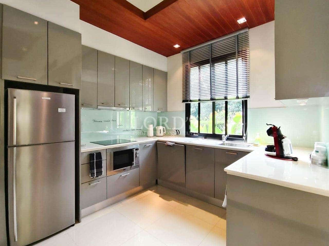 Modern L-shaped kitchen with gray cabinets, stainless steel appliances, white countertops, and large window.
