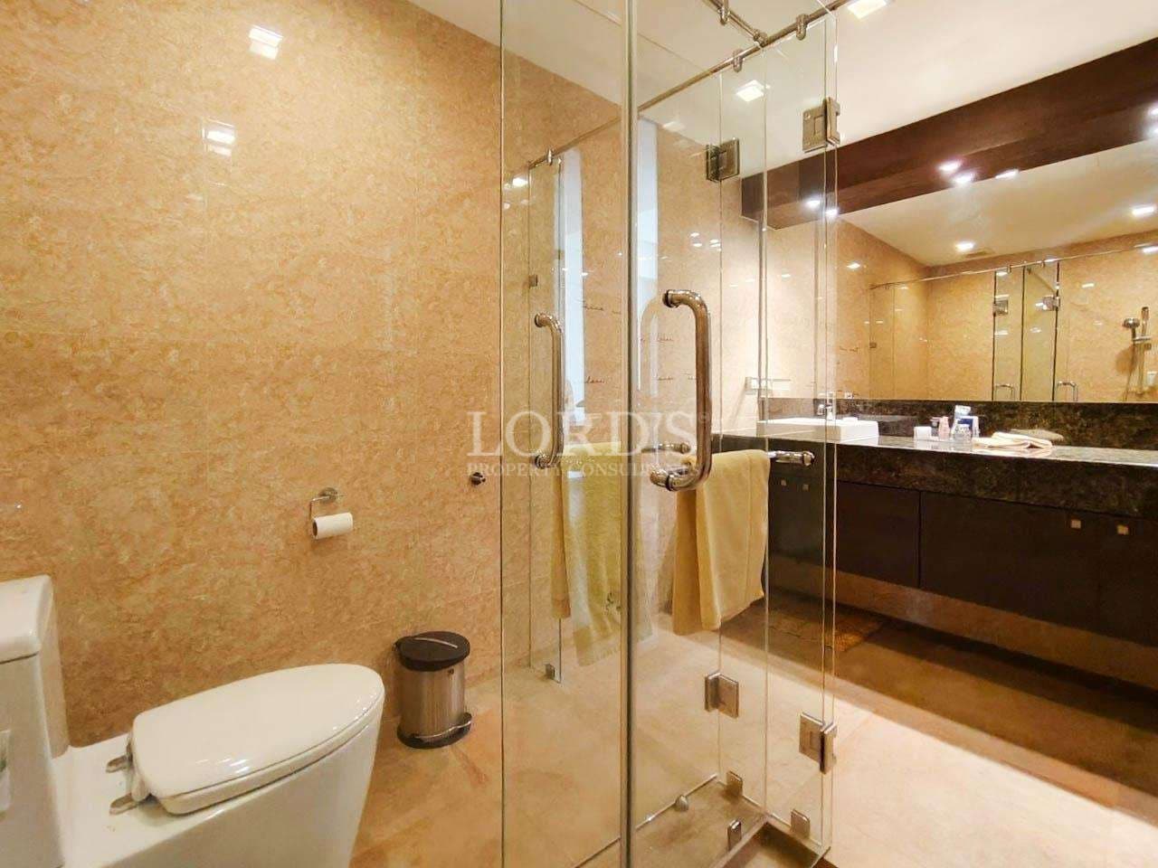 Modern bathroom with glass shower enclosure, marble walls, and double vanity in a luxury villa.