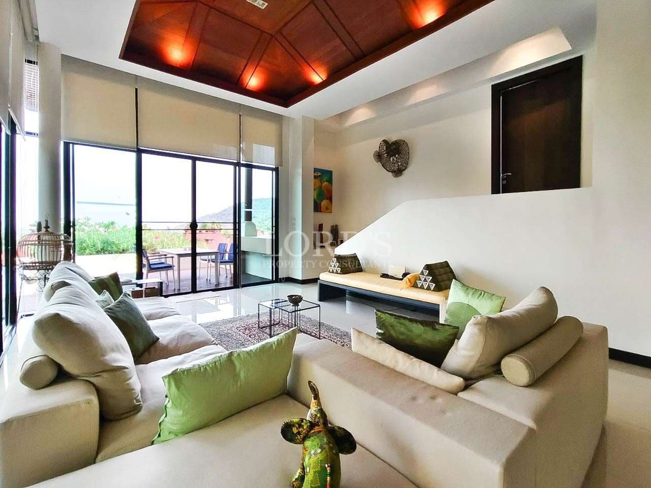 Modern living room with high ceiling, wooden recessed lighting, and terrace access in a luxury villa.