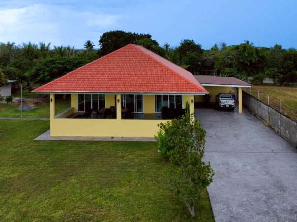Front exterior view of a single-story villa with red-tiled roof, private driveway, and covered parking.