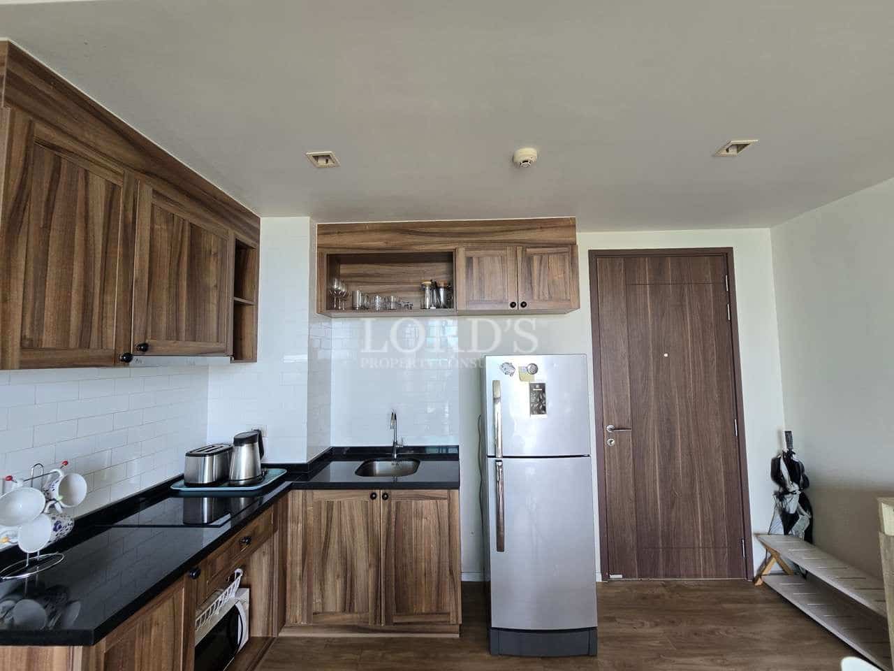 Modern kitchen with wooden cabinets, black countertop, sink, and refrigerator