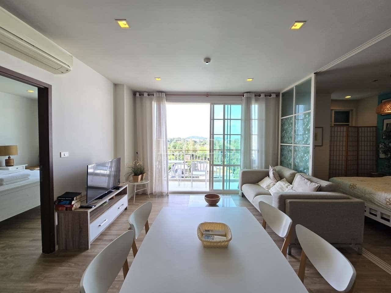 Modern apartment living and dining area with sofa, TV unit, and balcony access