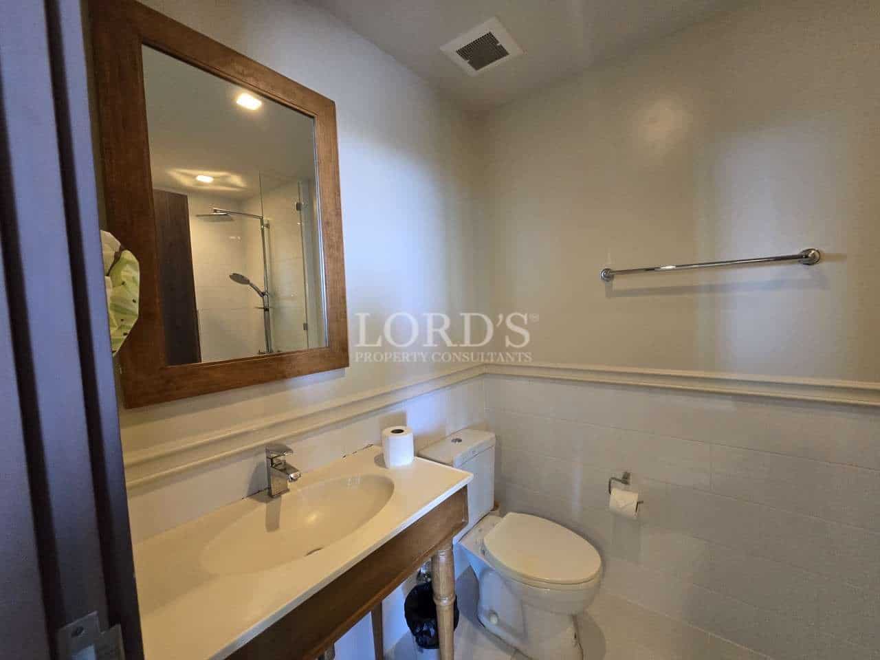 Modern bathroom with vanity sink, toilet, wall mirror, and towel bar