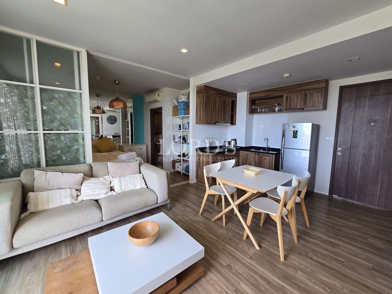 Modern open-plan apartment with sofa, dining table, kitchen, and wooden flooring