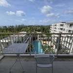 Apartment balcony with outdoor table and chairs overlooking swimming pool and residential buildings