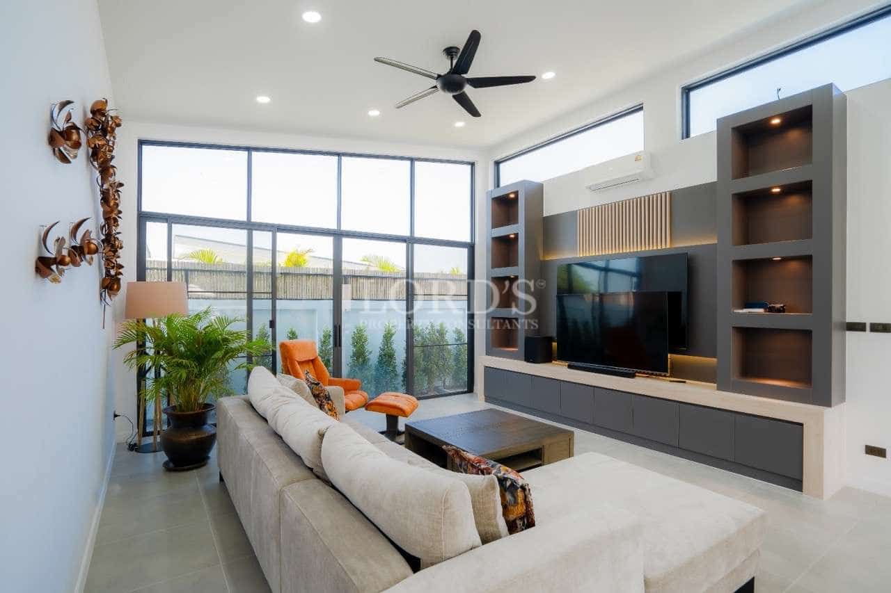 Modern living room with built-in TV wall unit, large glass windows, high ceiling, and contemporary furniture.
