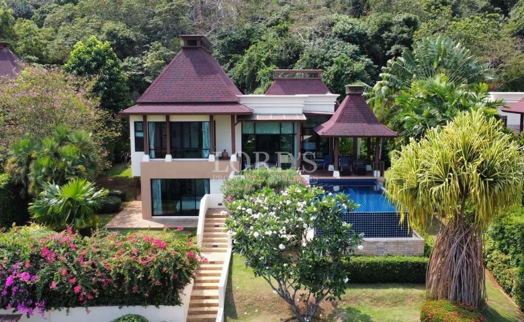 Luxury two-storey tropical villa with private swimming pool surrounded by lush greenery and hillside views.