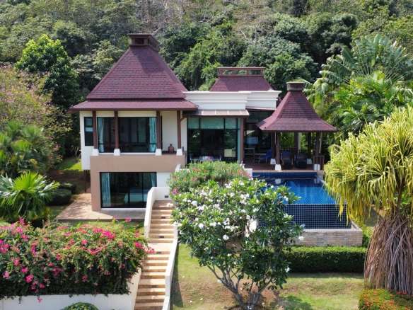 Luxury two-storey tropical villa with private swimming pool surrounded by lush greenery and hillside views.