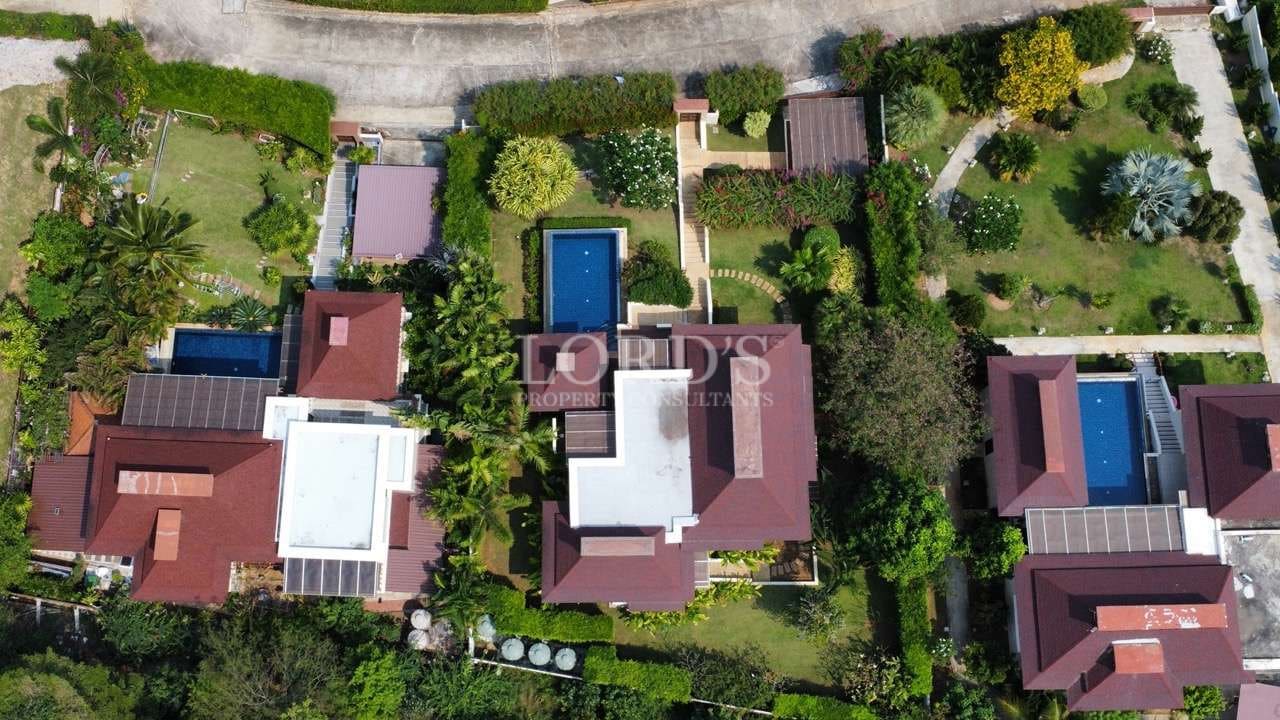 Top-down aerial view of luxury villas with private swimming pools and landscaped gardens.