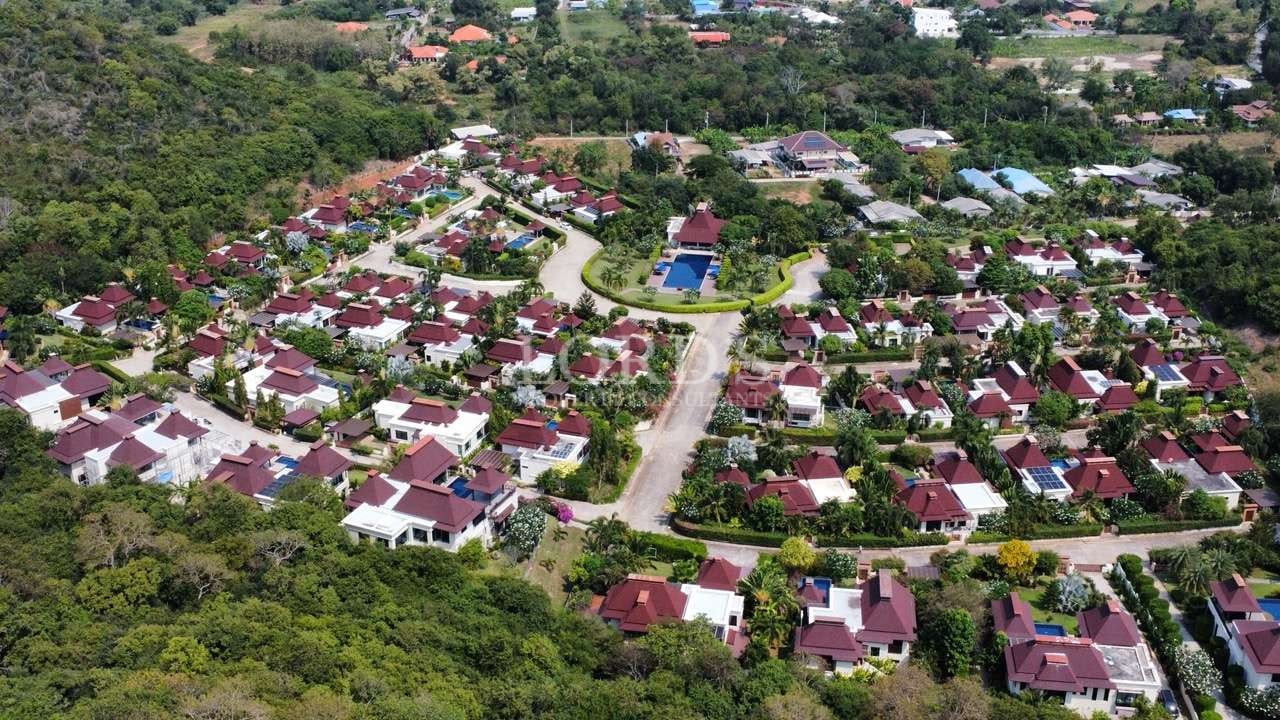 Aerial view of a luxury villa community surrounded by greenery and hills.