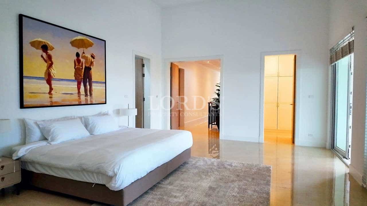 Modern luxury bedroom with king-size bed, minimalist décor, and large windows allowing natural light.