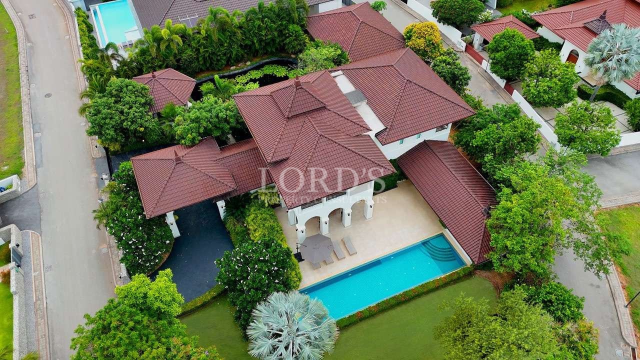 Aerial view of a luxury villa with red tiled roof, private swimming pool, and landscaped garden.