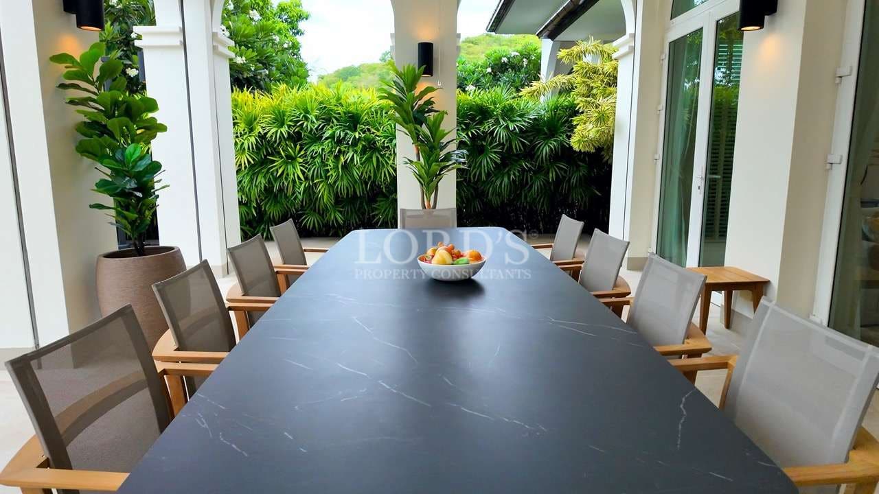 Outdoor dining area with modern table and chairs in a luxury villa garden patio.